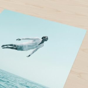 Imaginez un instant où la gravité abdique devant la course du soleil. Un homme, vêtu d'un lin immaculé, défie les lois de la physique pour se figer au-dessus d'un miroir d'azur. C'est ici que le tumulte de l'océan devient une prière silencieuse, invitant votre esprit à une dérive onirique et souveraine.